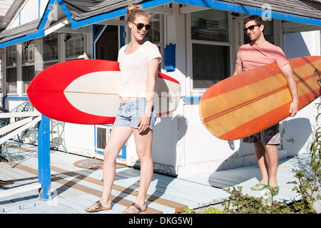 Matura sul patio che trasportano le tavole da surf, Breezy Point, Queens, a New York, Stati Uniti d'America Foto Stock