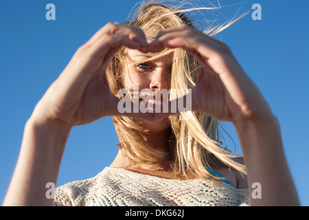 Ritratto di giovane donna facendo segno di cuore, Breezy Point, Queens, a New York, Stati Uniti d'America Foto Stock