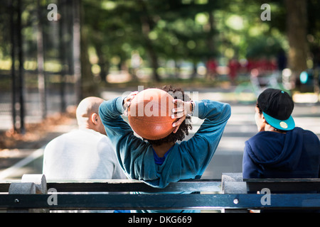 Giovani uomini seduti sul parco, una holding basket Foto Stock