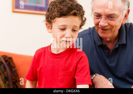 Ragazzo giovane e nonno in salotto Foto Stock