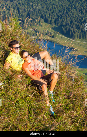 Coppia giovane giacente in montagna a prato in gruppo Osterhorn, Stato di Salisburgo, Austria Foto Stock