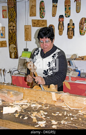 Donna cilena con uno scalpello e un martello carving maschera in legno a Los Dominicos artesans village a Santiago del Cile Foto Stock