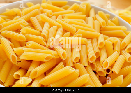 Una piastra con non cotti penne rigate su un tavolo, pronti per essere cotti Foto Stock