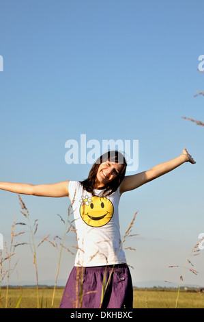Felice giovane donna sorridente all'aperto le braccia aperte Foto Stock