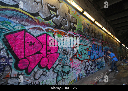 Un giovane maschio adulto Graffiti artist verniciatura in tunnel di Waterloo Londra Foto Stock