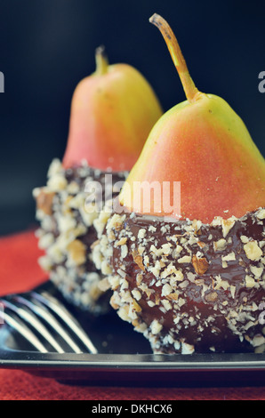 Due pere fresche con glassa di cioccolato e i dadi su sfondo nero Foto Stock