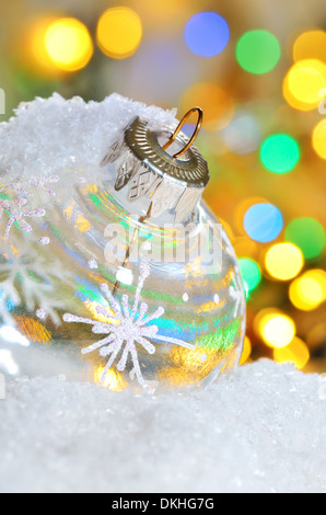 Trasparente palla di Natale sulla neve in inverno e le luci gialle Foto Stock