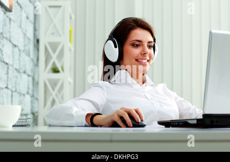 Giovane imprenditrice nelle cuffie al lavoro su un notebook in ufficio Foto Stock