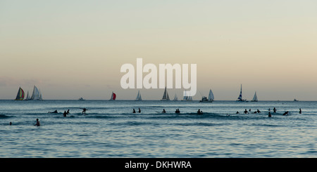 Surf e barche a vela nell'oceano al tramonto, Waikiki, Honolulu Oahu, Hawaii, STATI UNITI D'AMERICA Foto Stock