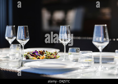 Inserire le impostazioni sull'elegante tavolo da pranzo Foto Stock