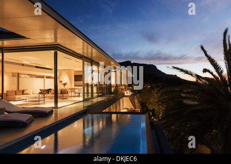 Casa moderna che affaccia sulle montagne al tramonto Foto Stock
