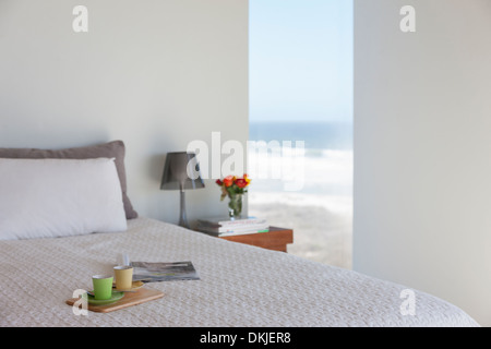 Vassoio con tazzine sul letto in camera da letto con vista oceano Foto Stock