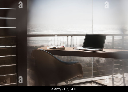 Laptop sulla scrivania in modern home office con vista sull'oceano Foto Stock