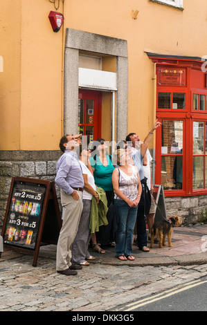 Un gruppo di uomini e donne alla ricerca come una guida turistica evidenzia un elemento di interesse durante un tour guidato di Plymouth Foto Stock