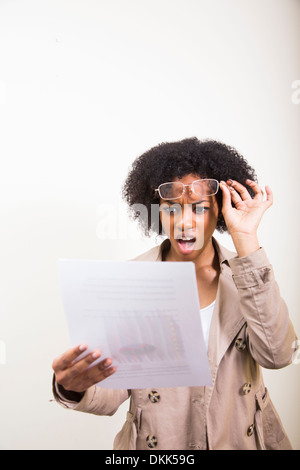 Giovane africano donna americana la lettura dei documenti guardando scioccato Foto Stock