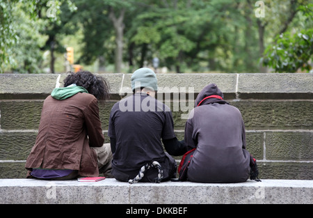 Vista posteriore di tre ragazzi seduti su una parete di Central Park a New York Foto Stock