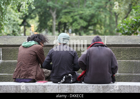 Vista posteriore di tre ragazzi seduti su una parete di Central Park a New York Foto Stock