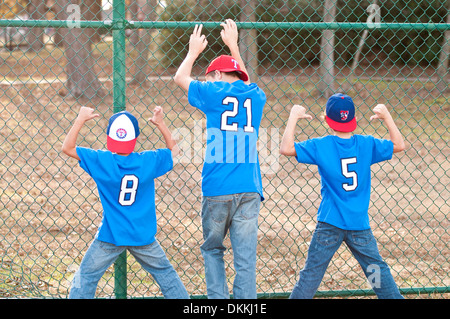 Tre fratelli accanto al recinto a baseball park. Foto Stock