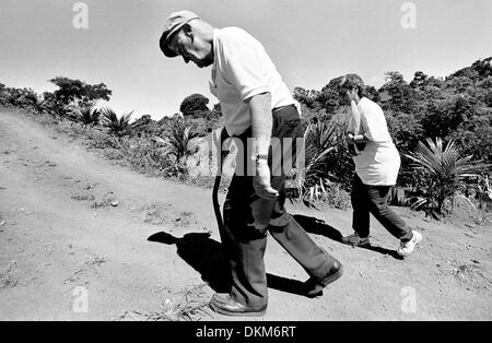 Nov. 19, 2002 - Managua, Nicaragua - la camminata su per una ripida e polverosa strada torna al bus sotto il caldo America Centrale sole di mezzogiorno permette ai pellegrini Padre Edward Maloney e Aurora Salazar all esperienza di che cosa è come camminare nei panni dei poveri, che raramente hanno il lusso di un veicolo per ottenere da luogo a luogo. Maloney, 73, un sacerdote in pensione, ha detto: "è importante ottenere questo abete Foto Stock