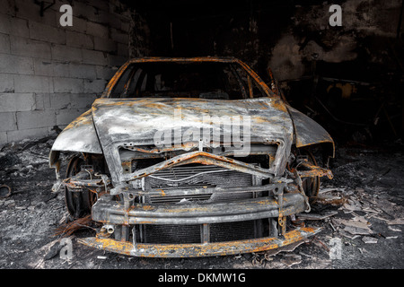 Vicino la foto di un bruciato auto nel garage dopo il fuoco per uso grunge Foto Stock