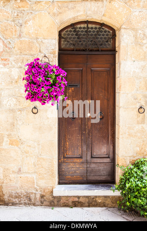 Pienza, Regione Toscana, Italia. La vecchia porta di legno con fiori Foto Stock