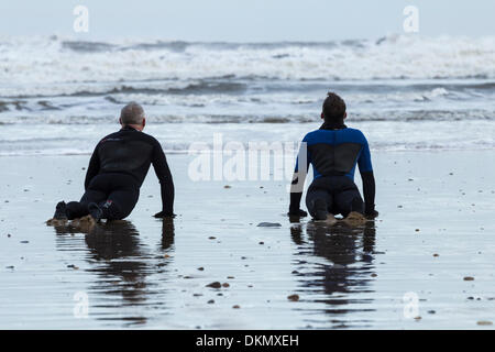 Surfers stretching a Saltburn spiaggia in inverno. Saltburn dal mare, North Yorkshire, Inghilterra, Regno Unito Foto Stock