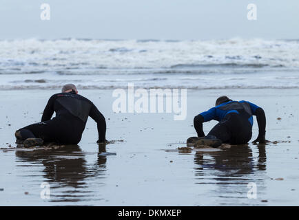 Surfers stretching a Saltburn spiaggia in inverno. Saltburn dal mare, North Yorkshire, Inghilterra, Regno Unito Foto Stock