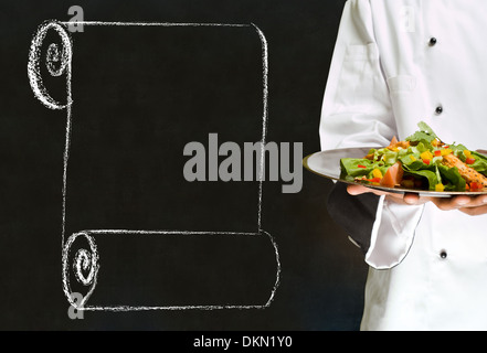 Lo Chef azienda sanitaria piatto di insalata con chalk scorrere su sfondo blackboard Foto Stock