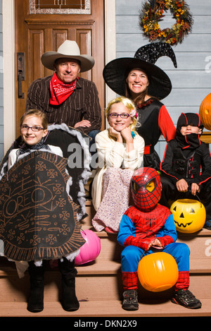 Una famiglia di genitori e tre bambini vestiti in costume per Halloween trucco-o-trattare Foto Stock