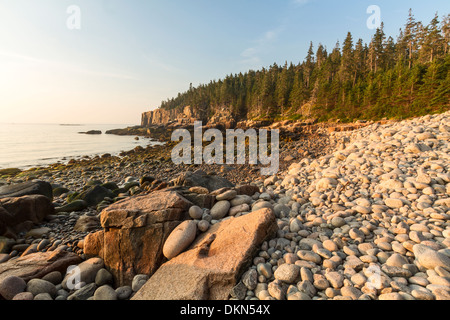 Pietre arrotondate sulla spiaggia di Boulder guardando verso la lontra scogliere a sunrise nel Parco Nazionale di Acadia, Maine Foto Stock