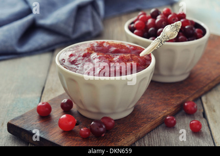 Salsa di mirtilli in vaso di ceramica con bacche fresche su sfondo di legno Foto Stock