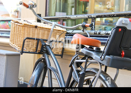 Bicicletta con cesto in vimini sorge vicino a parete Foto Stock