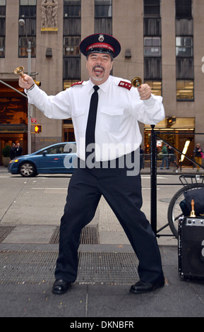 Un esercito della salvezza volontario cantare, ballare e suonare le campane durante la raccolta in Midtown Manhattan, a New York City Foto Stock