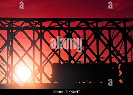 Treni attraversando il vecchio ponte in sunset Foto Stock