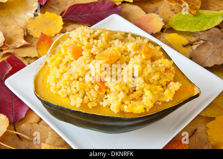 Acorn squash ripiene di cuscus e albicocche con colorate Foglie di autunno Foto Stock