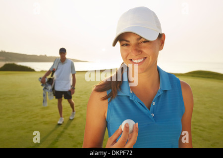Donna che mantiene la pallina da golf sul corso Foto Stock