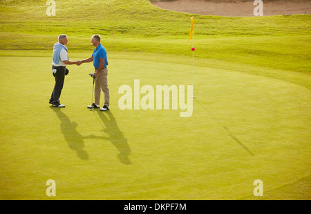 Alti uomini stringono le mani sul campo da golf Foto Stock