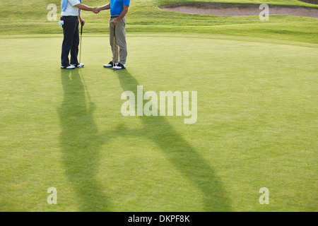 Alti uomini stringono le mani sul campo da golf Foto Stock