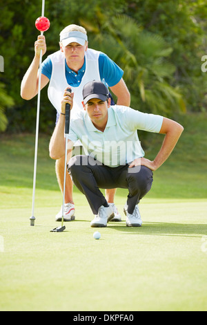 Caddy e giocatore di golf sul putting green Foto Stock