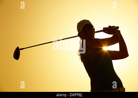 Silhouette di donna giocando a golf sul corso Foto Stock