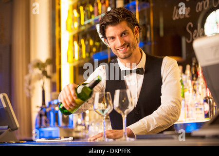 Ritratto di ben vestito barista versando il vino nel bar di lusso Foto Stock