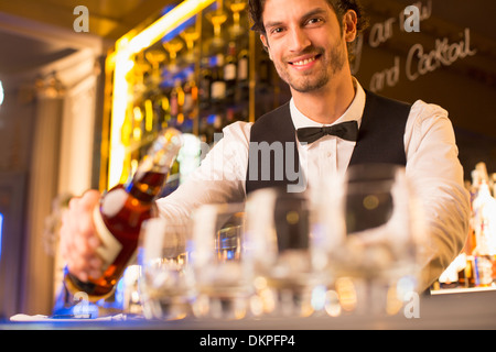 Ritratto di ben vestito barista versando Borbone nel bar di lusso Foto Stock
