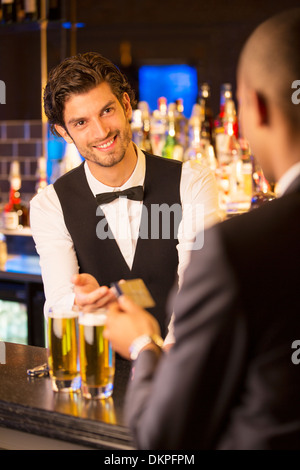 Ben vestito barista prendendo carta di credito dal cliente nel bar di lusso Foto Stock