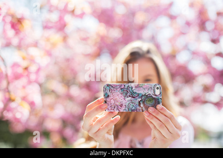 Donna prendendo autoritratto con un telefono cellulare all'aperto Foto Stock