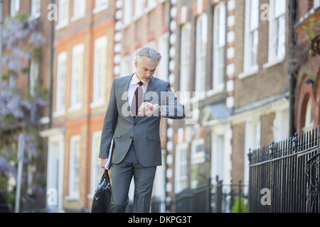 Imprenditore controllo orologio da polso sul marciapiede urbano Foto Stock