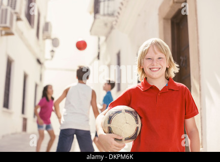 Ragazzo tenendo palla calcio in vicolo Foto Stock