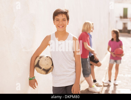 Ragazzo tenendo palla calcio in vicolo Foto Stock