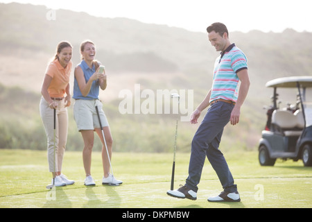 Le donne a guardare l uomo saldo golf club a piedi Foto Stock