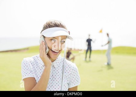 Donna che parla su telefono cellulare sul campo da golf Foto Stock