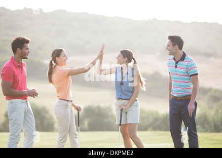 Gli amici di alta fiving sul campo da golf Foto Stock